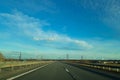 A road or highway leading to the horizon. View from the car window. Northern dim summer, blue sky with white clouds. Royalty Free Stock Photo