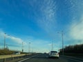 A road or highway leading to the horizon. View from the car window. Northern dim summer, blue sky with white clouds Royalty Free Stock Photo