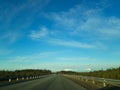 A road or highway leading to the horizon. View from the car window. Northern dim summer, blue sky with white clouds Royalty Free Stock Photo