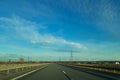 A road or highway leading to the horizon. View from the car window. Northern dim summer, blue sky with white clouds. Royalty Free Stock Photo