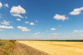 Road highway near harvested mowed golden wheat field on bright summer or autumn day against vibrant blue sky on Royalty Free Stock Photo