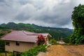 The road and houses in the village on the slopes of the mountains with clouds. Sabah, Borneo, Malaysia