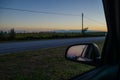 Road from the inside of a car and the reflection of the rear-view mirror of the car. road trip at sunset