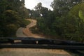 Road through jungle, view behind windshield of car. Dangerous upward climb Royalty Free Stock Photo