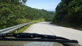 Road through jungle, view behind windshield of car Royalty Free Stock Photo