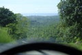 Road through jungle, view behind windshield of car. Palm trees and sea in background Royalty Free Stock Photo