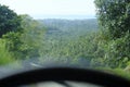 Road through jungle, view behind windshield of car. Palm trees and sea in background Royalty Free Stock Photo