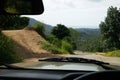 Road through jungle, view behind windshield of car. Palm trees and sea in background Royalty Free Stock Photo