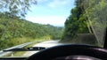 Road through jungle, view behind windshield of car. Palm trees and sea in background Royalty Free Stock Photo