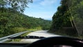 Road through jungle, view behind windshield of car Royalty Free Stock Photo