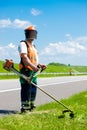 Road landscapers cutting grass using string lawn trimmers Royalty Free Stock Photo