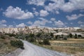 Road leading to beautiful desert rocky sandstone valley with huge troglodytes in blue sky with clouds Royalty Free Stock Photo