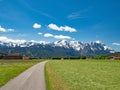 A road leads through the landscape of Upper Bavaria towards Wetterstein Mountains and Zugspitze, Bavaria, Germany