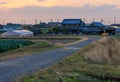 Road leads to large Japanese family home with fields and greenhouse in farming village at sunrise