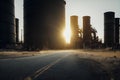 a road with a lot of large tanks in the background and a sun setting behind it in the distance