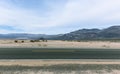 Road in Mojave desert with cloudy sky and striped mountains