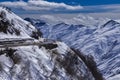 The road through the mountain pass the ridge of the Greater Caucasus. The tops of the mountains covered with snow Royalty Free Stock Photo