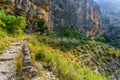 Road between mountains in the rocky canyon with hikers walking in a row. Royalty Free Stock Photo