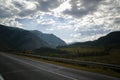 Road in mountains valley and storm clouds on a dark sky