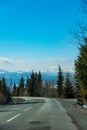 Road near the mountains. Asphalt road with trees near, winter mountain in background. Blue sky. Royalty Free Stock Photo