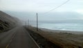 Road next to the ocean on a foggy day