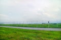 Road Outside Airport Lined by a Wire Fence with green grass and brigth sky