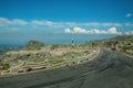 Road over hilly landscape covered by rocks and bushes