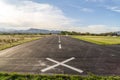 Road painted with broken white lines and an X mark under cloudy blue sky