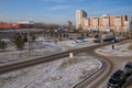 The road with parking and a public garden on the background of residential houses in winter.