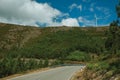 Road passing through hilly landscape with wind turbines Royalty Free Stock Photo