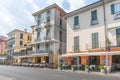 Road past traditional European buildings with cafe and restaurant tables with white cloths on path at Menaggio, Italy