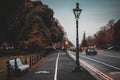 Road beside the peaceful Phoenix Park in Dublin. Perspective view of the bicycle way with bench and street lamps around and a real