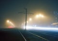Road with poles with high-voltage wires and tram tracks or tram rails , evening fog on the streets, poles with high-voltage wires Royalty Free Stock Photo