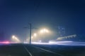 Road with poles with high-voltage wires and tram tracks or tram rails , evening fog on the streets, poles with high-voltage wires Royalty Free Stock Photo