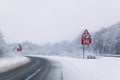 Road with Reduce speed now sign during snow fall Royalty Free Stock Photo