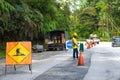 Road repair in Asia. Fenced road section with a pit. Workers overalls