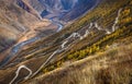 The road is rocky along the mountain slope, descending into the valley of the mountain river. Altai, Russia.