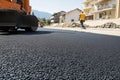 Road Roller Compacting Asphalt on Street with Worker and City in Background Royalty Free Stock Photo