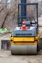 Road roller at a construction site against the background of a sidewalk under construction. Vertical image