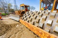 Road roller with spikes and earthmover are working at construction site