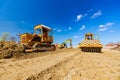 Road roller with spikes and earthmover are working at construction site Royalty Free Stock Photo