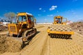 Road roller with spikes and earthmover are working at construction site Royalty Free Stock Photo