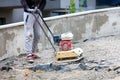 A construction worker compacts crushed stone with a petrol vibratory compactor