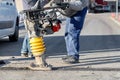 Road service workers use a petrol vibratory rammer to repair a section of the road