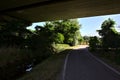 Road in the shade passing under a viaduct in the italian countryside in summer Royalty Free Stock Photo