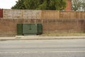 Road side green telecoms cabinet in front of brick wall & fence in Great Blakenham.