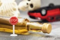 Road sign, a bottle of whiskey, a skeleton and an inverted car. Concept on the topic of drunk driver