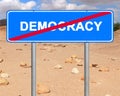 Road sign. Democracy termination location mark opposite the stony desert landscape. Word democracy crossed out with a red line Royalty Free Stock Photo