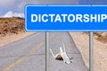 Road sign. Dictatorship location mark. The word is written on a blue signboard located opposite the old empty road with broken tra