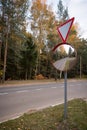 Road sign - give way and outdoor convex protective mirror with a reflection of the urban road look car